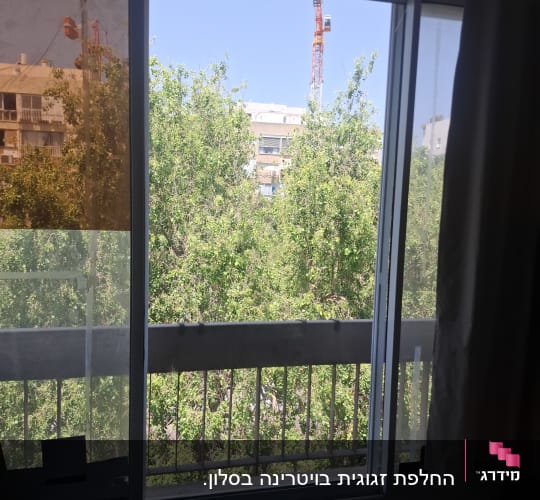 חלון זכוכית עם נוף לעצים ומנוף ברקע